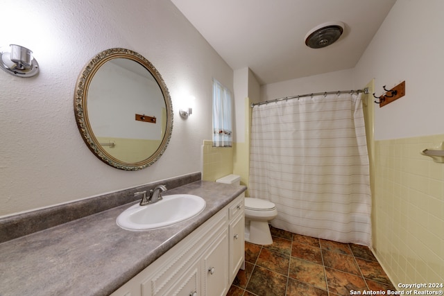 bathroom featuring vanity, toilet, and tile walls