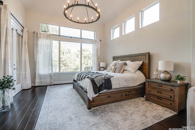 bedroom with dark hardwood / wood-style flooring, a towering ceiling, and a notable chandelier