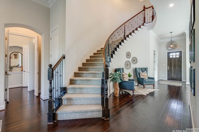 staircase with crown molding, a towering ceiling, and hardwood / wood-style flooring