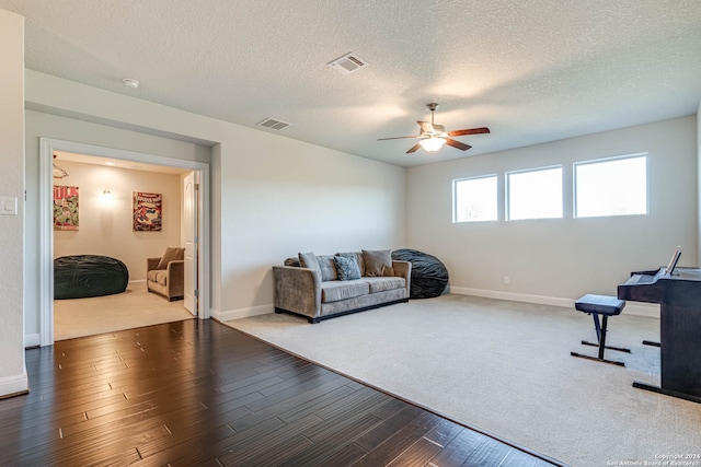 living room with hardwood / wood-style floors, a textured ceiling, and ceiling fan