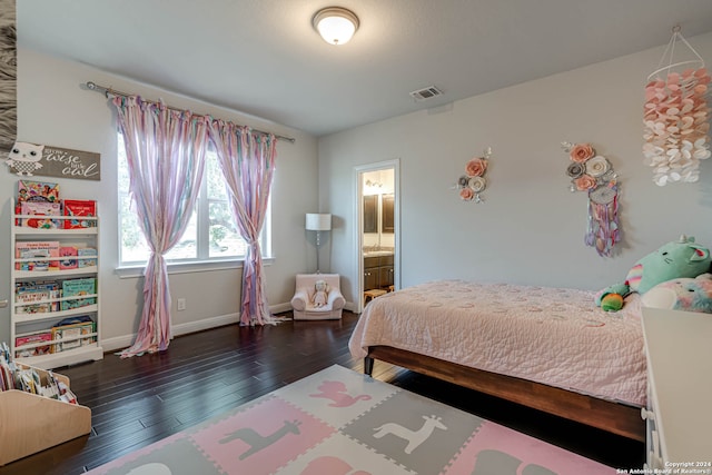 bedroom featuring ensuite bath and dark wood-type flooring