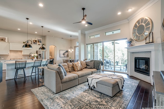 living room with dark hardwood / wood-style floors, sink, ornamental molding, and ceiling fan with notable chandelier