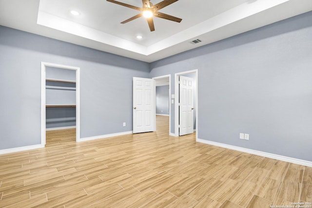 5882 Castle Run, San Antonio, TX 78218 - unfurnished bedroom featuring a raised ceiling, baseboards, light wood-style floors, a spacious closet, and recessed lighting