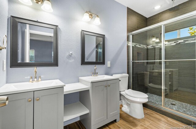 5882 Castle Run, San Antonio, TX 78218 - full bathroom with toilet, a stall shower, two vanities, and wood finished floors
