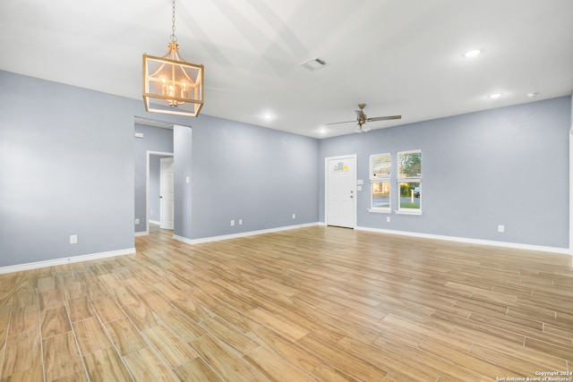 empty room with light hardwood / wood-style flooring and ceiling fan with notable chandelier