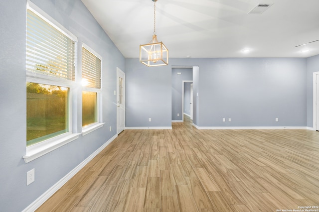 empty room with a chandelier and light wood-type flooring