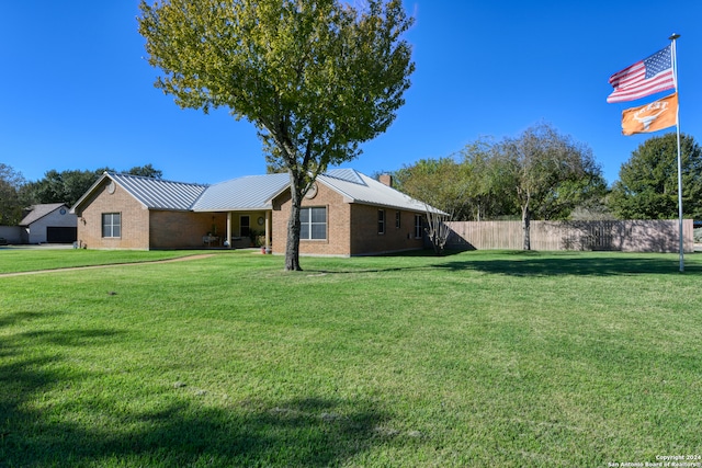 view of home's exterior featuring brick siding, a yard, a chimney, metal roof, and fence