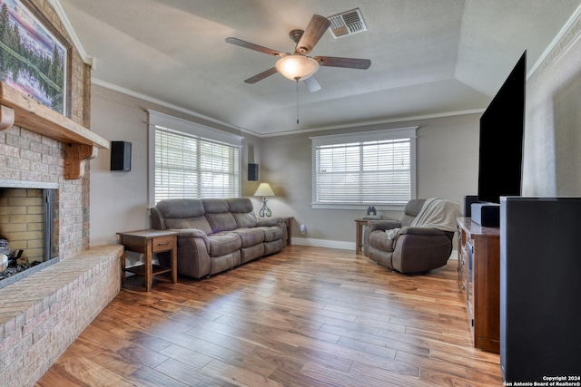 1333 Continental Dr S, Pleasanton, TX 78064 - living area featuring a ceiling fan, a brick fireplace, ornamental molding, hardwood / wood-style flooring, and a tray ceiling