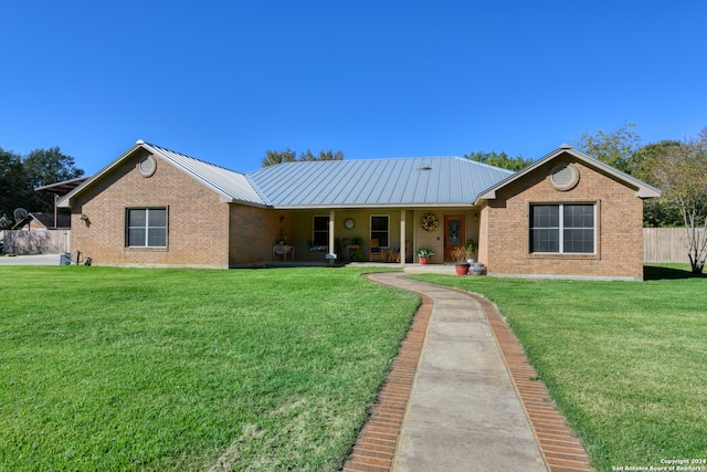 ranch-style home with brick siding, metal roof, and a front lawn