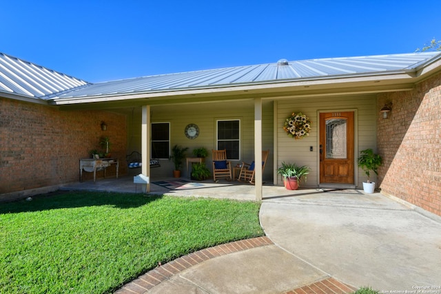 1333 Continental Dr S, Pleasanton, TX 78064 - property entrance featuring a yard, metal roof, a standing seam roof, a patio area, and brick siding
