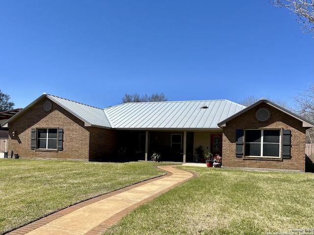 ranch-style house featuring a front yard, a standing seam roof, brick siding, and metal roof