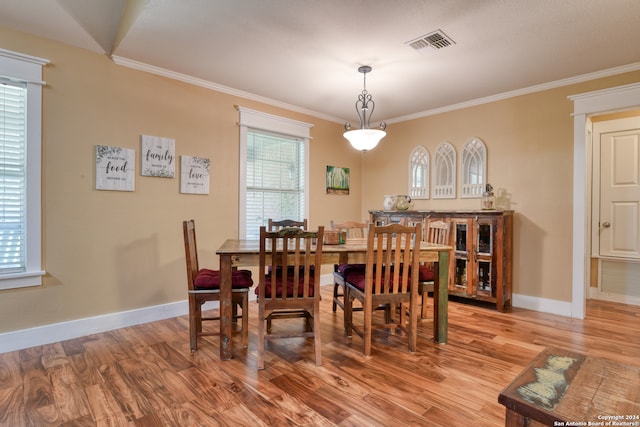 dining space with baseboards, crown molding, visible vents, and wood finished floors