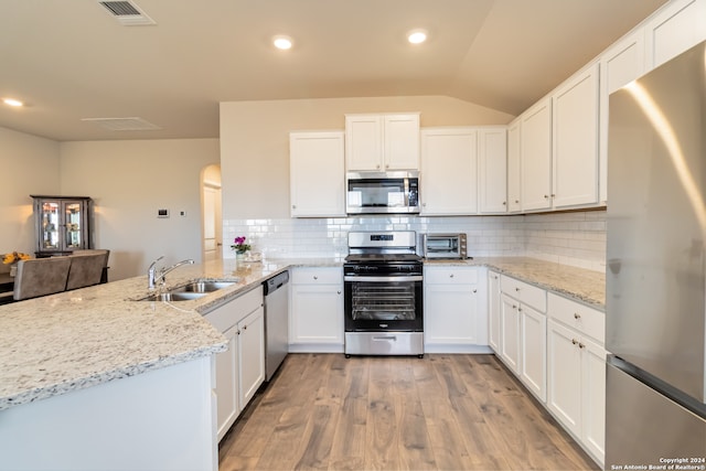 kitchen featuring white cabinets, light stone countertops, light wood-type flooring, kitchen peninsula, and stainless steel appliances