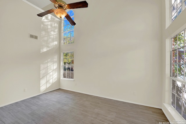 spare room with hardwood / wood-style flooring, ceiling fan, a towering ceiling, and crown molding