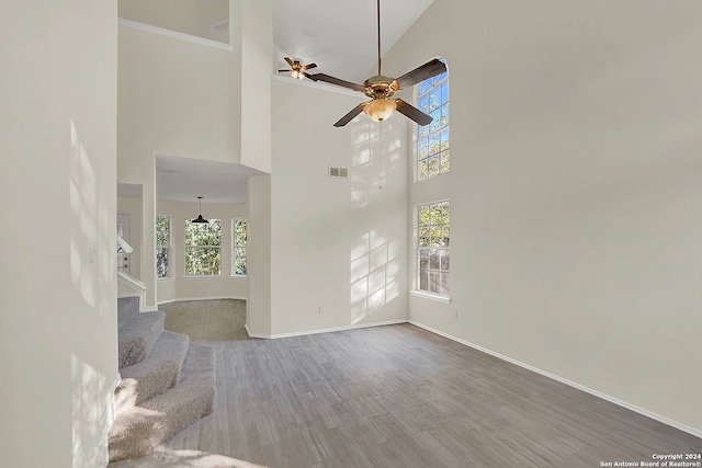 unfurnished living room with ceiling fan, high vaulted ceiling, a healthy amount of sunlight, and hardwood / wood-style flooring