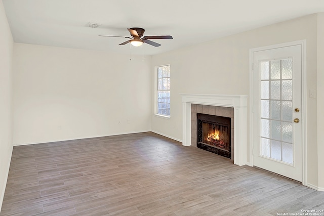 unfurnished living room featuring ceiling fan, light wood-type flooring, and a fireplace