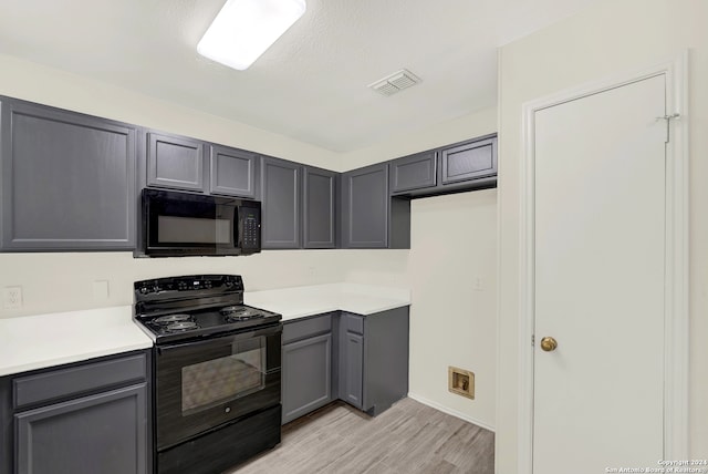 kitchen with gray cabinets, black appliances, a textured ceiling, and light hardwood / wood-style floors