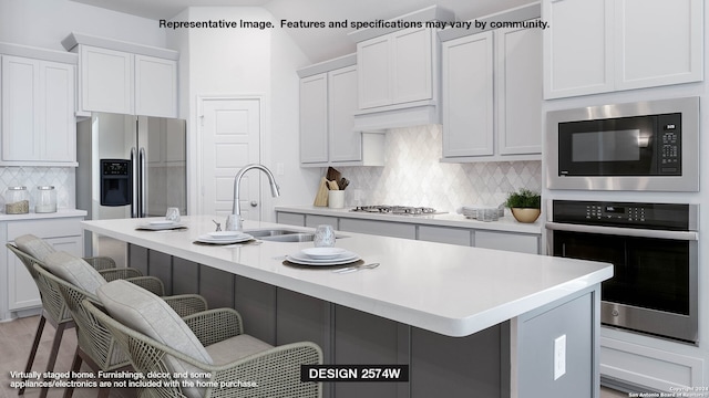 kitchen with decorative backsplash, a breakfast bar, stainless steel appliances, light countertops, and a sink