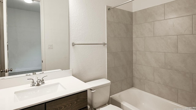 bathroom featuring shower / washtub combination, a textured wall, vanity, and toilet