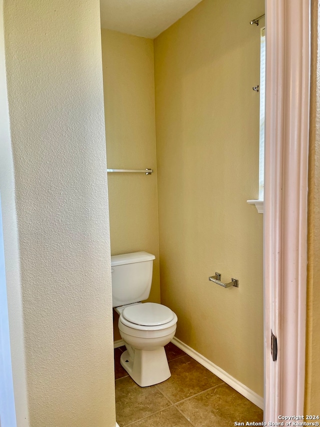 bathroom with tile patterned flooring, toilet, and a healthy amount of sunlight