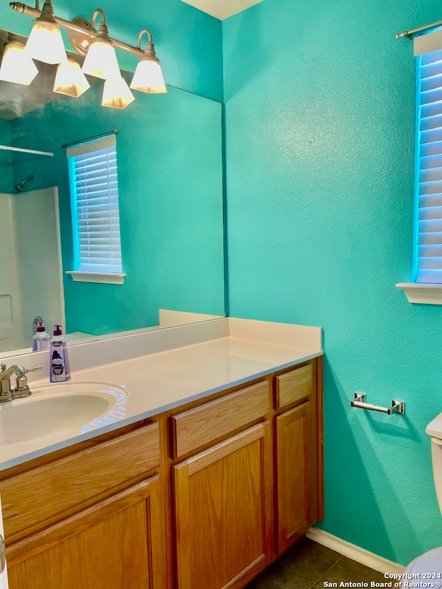 bathroom with tile patterned floors, vanity, a healthy amount of sunlight, and toilet