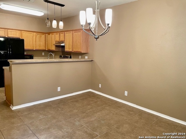 kitchen with sink, hanging light fixtures, an inviting chandelier, black fridge, and kitchen peninsula