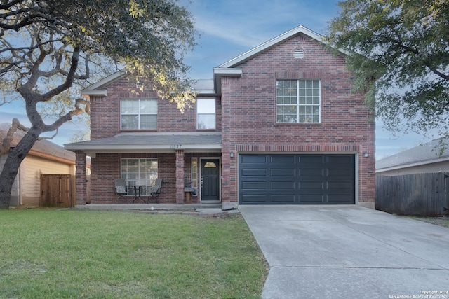 front facade featuring covered porch, a garage, and a front lawn