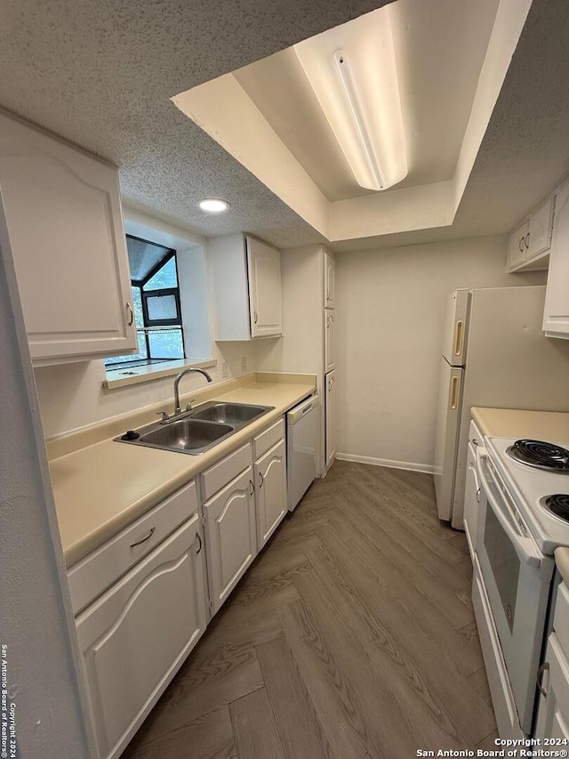 kitchen featuring white cabinets, white appliances, a raised ceiling, and sink