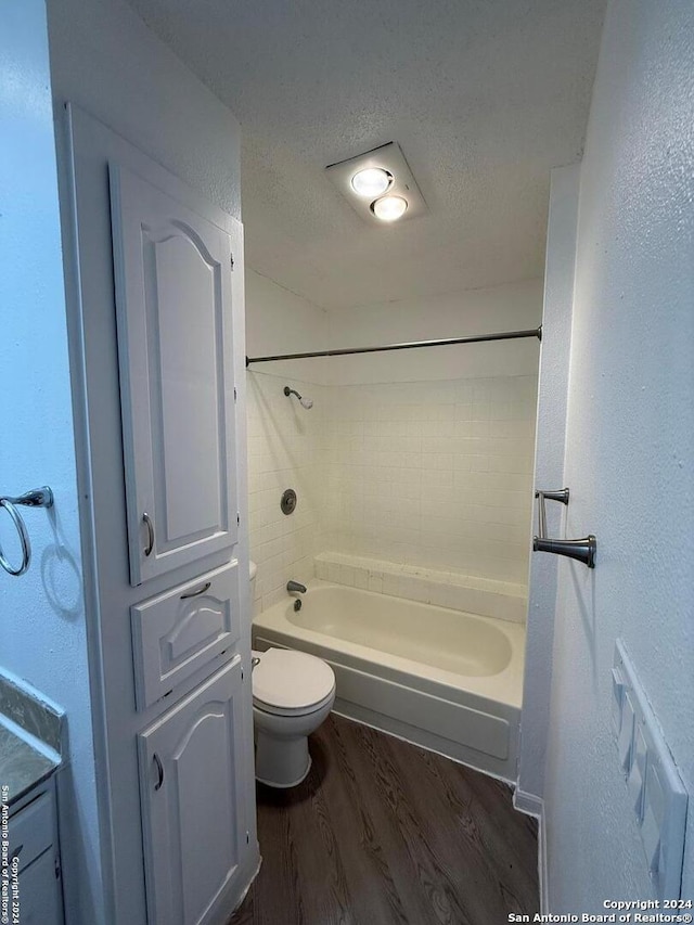 bathroom featuring hardwood / wood-style floors, a textured ceiling, toilet, and tiled shower / bath