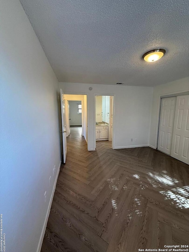 empty room featuring dark parquet floors and a textured ceiling