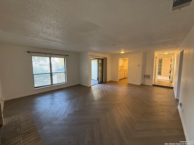 unfurnished living room featuring dark parquet floors and a textured ceiling