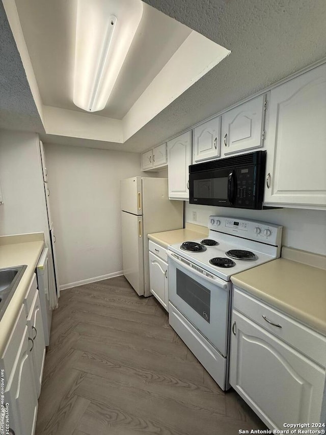 kitchen with sink, a raised ceiling, light hardwood / wood-style flooring, white appliances, and white cabinets