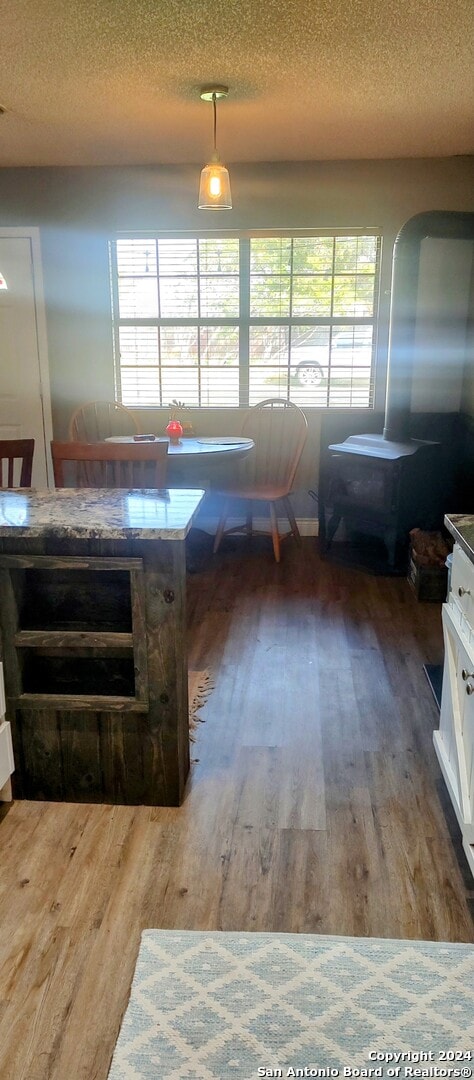 dining space with hardwood / wood-style flooring, a healthy amount of sunlight, and a textured ceiling