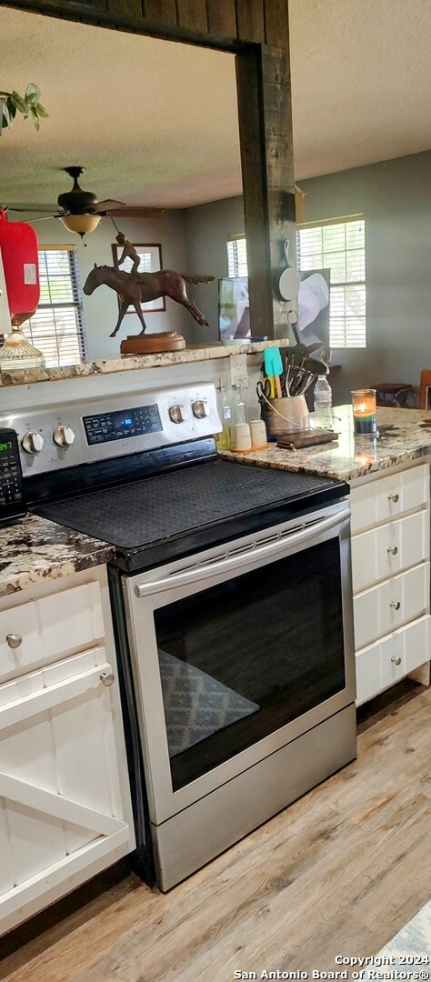 kitchen featuring white cabinets, a healthy amount of sunlight, light wood-type flooring, and electric stove