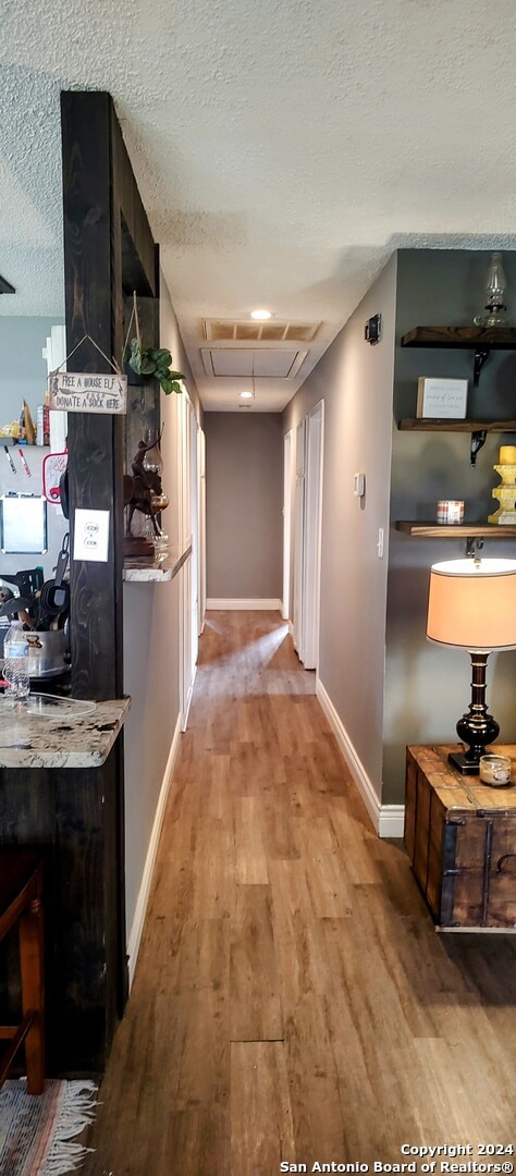 hall featuring a textured ceiling and hardwood / wood-style flooring