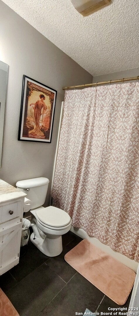 bathroom with vanity, a textured ceiling, toilet, and tile patterned flooring