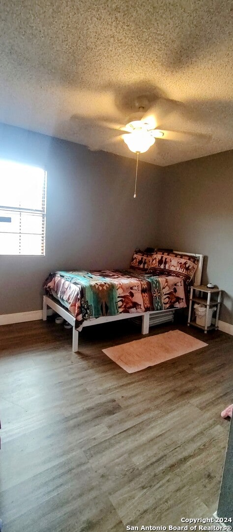 unfurnished bedroom featuring ceiling fan, wood-type flooring, and a textured ceiling