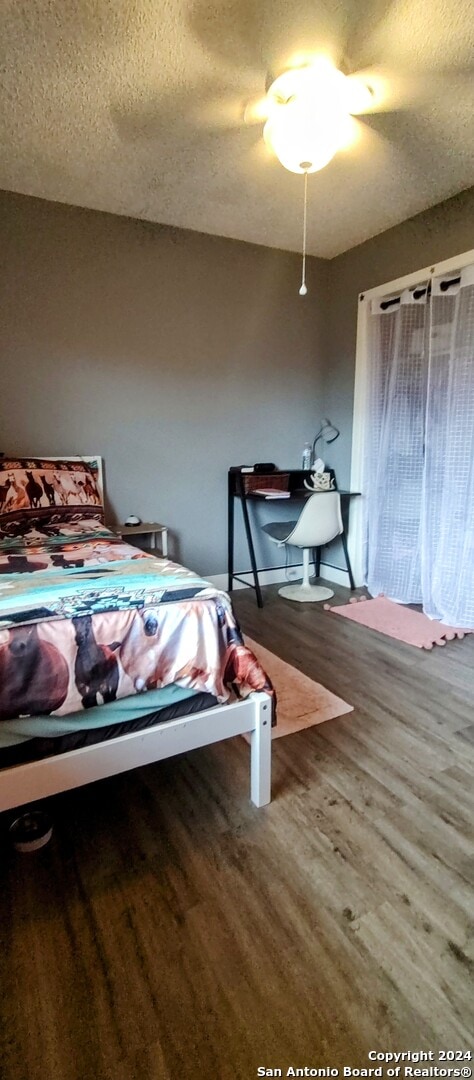 bedroom featuring hardwood / wood-style floors, ceiling fan, and a textured ceiling