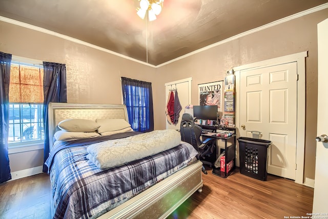 bedroom with a closet, hardwood / wood-style flooring, ceiling fan, and crown molding