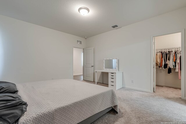 carpeted bedroom featuring a spacious closet and a closet