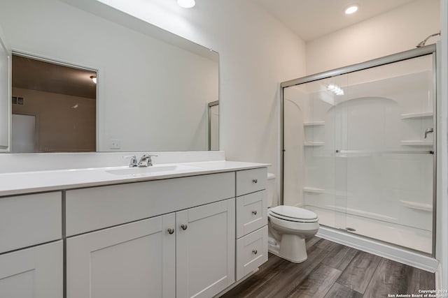 bathroom featuring hardwood / wood-style floors, vanity, a shower with shower door, and toilet