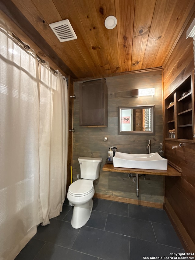 bathroom featuring tile patterned floors, wood walls, wooden ceiling, and toilet