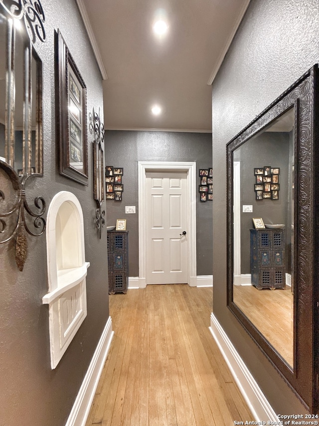 corridor featuring light wood-type flooring and ornamental molding