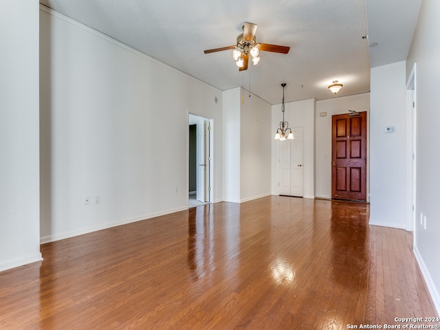 unfurnished living room with a textured ceiling, ceiling fan with notable chandelier, and hardwood / wood-style flooring