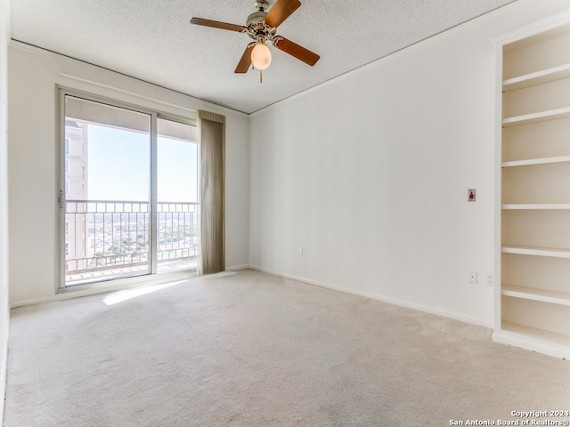 carpeted empty room featuring built in shelves, ceiling fan, and a textured ceiling