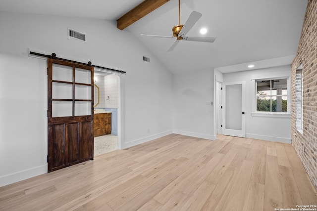 unfurnished living room featuring brick wall, ceiling fan, lofted ceiling with beams, a barn door, and light hardwood / wood-style floors