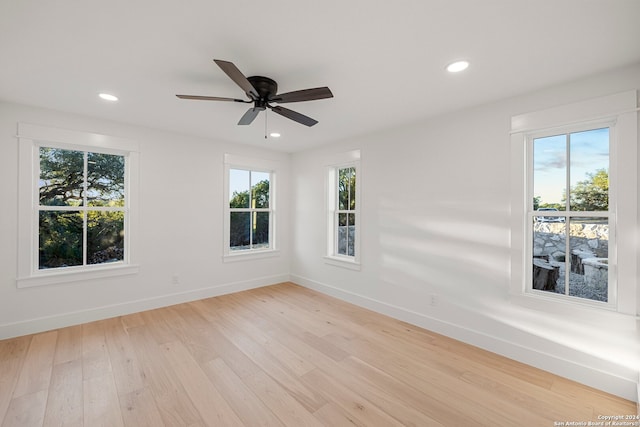 spare room featuring light wood-type flooring, ceiling fan, and a healthy amount of sunlight