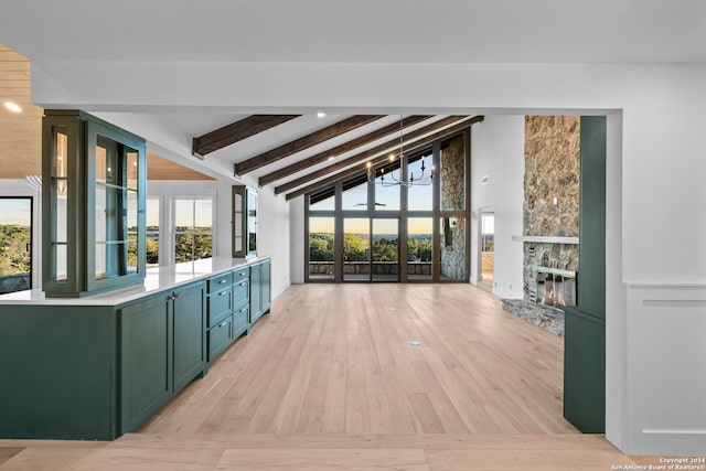 kitchen with a stone fireplace, plenty of natural light, vaulted ceiling with beams, and an inviting chandelier