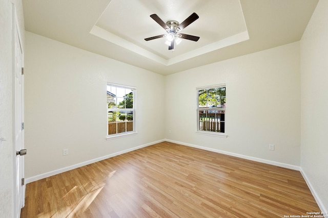 unfurnished room featuring ceiling fan, a raised ceiling, and light hardwood / wood-style flooring