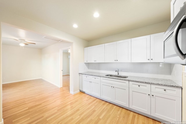 kitchen featuring white cabinets, decorative backsplash, light hardwood / wood-style floors, and sink